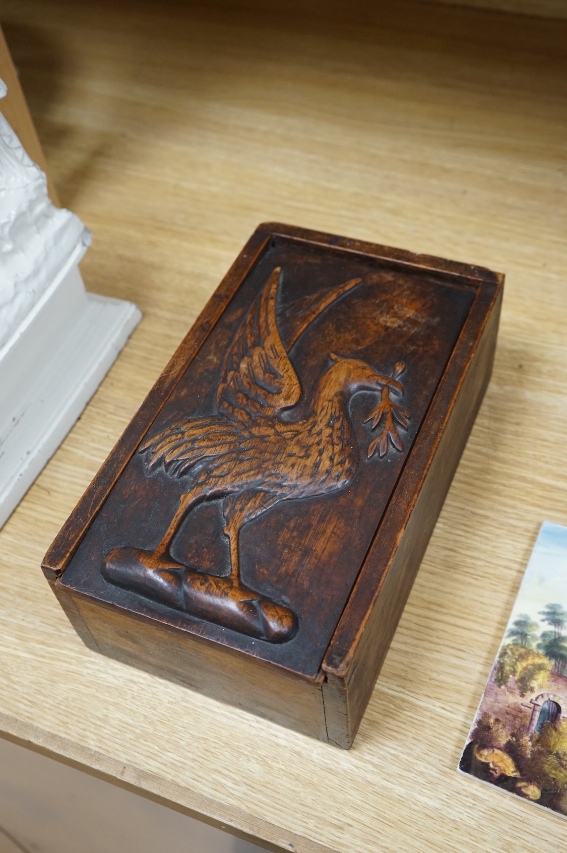 A 19th century games box with sliding cover carved with an eagle. The box containing a part bone stained chess set, box 28cm deep